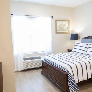 A cozy bedroom with a striped bedspread and natural light flowing through a window.