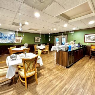 A cozy restaurant interior with neatly arranged tables and chairs, featuring a warm wooden floor and tasteful decor.