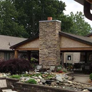 A cozy house with a stone chimney surrounded by a landscaped garden.