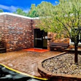 A brick building entrance with a tree and paved walkway on a sunny day.