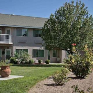 A residential apartment building with landscaped gardens and trees.