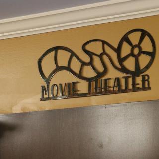 A decorative movie theater sign featuring a film reel design.