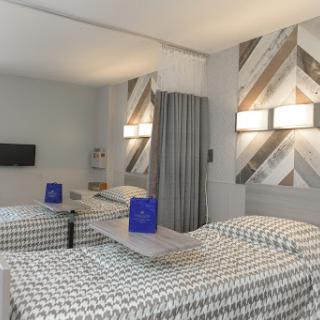 A modern hotel room featuring double beds with checkered bedding and stylish wall decor.