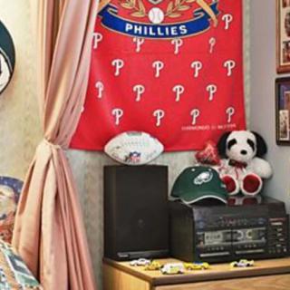 A room decorated with Philadelphia Phillies memorabilia, featuring a banner, stuffed animal, and sports gear.