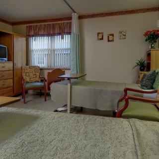 A hospital room with a patient bed, television, and seating area.