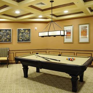 A well-lit billiard room featuring a pool table, comfortable seating, and decorative artwork on the walls.