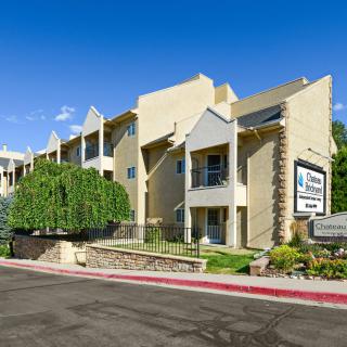 A modern apartment building with well-maintained landscaping and clear blue sky.