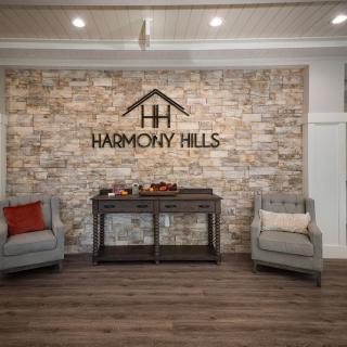 A cozy waiting area with two chairs, a table, and a brick wall featuring the 'Harmony Hills' signage.