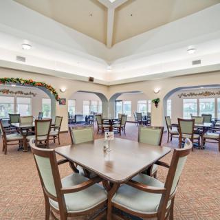 A spacious dining area featuring multiple tables and chairs, with elegant lighting and decor.