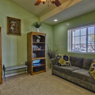 A cozy living room with green walls, featuring a bookshelf and a comfortable sofa.