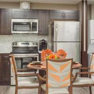 A modern kitchen with stainless steel appliances and a cozy dining area adorned with vibrant orange flowers.
