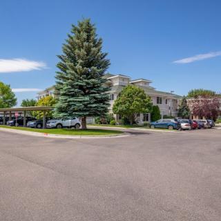 A building surrounded by trees and a parking lot with cars under a clear blue sky.