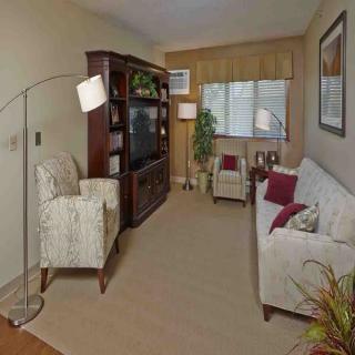 A cozy living room with a sofa, armchairs, a television set, and decorative elements.