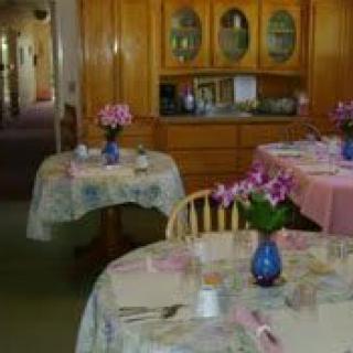 A cozy dining area with tables set with floral centerpieces and pastel tablecloths.