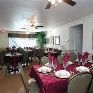Elegantly set tables in a formal dining room with red tablecloths and neatly arranged place settings.