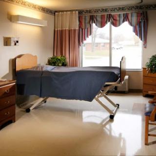A well-lit hospital room featuring a single bed and simple furnishings.