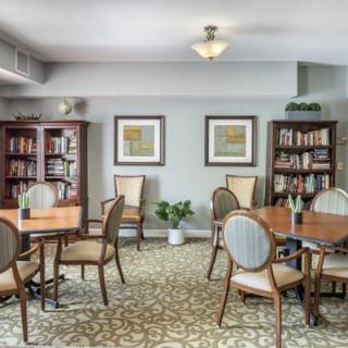 A cozy library room with bookshelves, tables, and chairs arranged for reading and study.