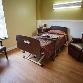 A clean and organized hospital room featuring a bed, chair, and window.