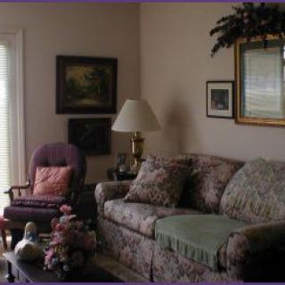 A cozy living room with a floral sofa, armchair, and decorative elements.