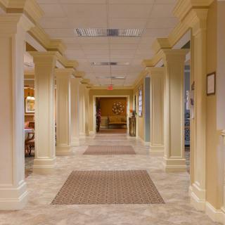 A well-lit interior hallway with columns and carpeting.