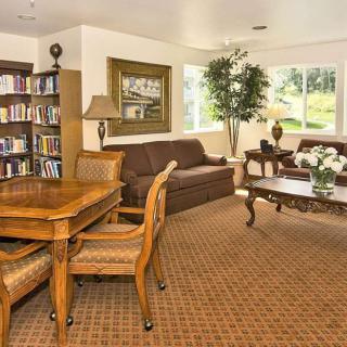 A cozy living room with a sofa, coffee table, bookshelf, and seating area.
