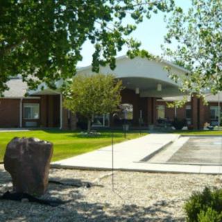 A view of a building surrounded by trees with a driveway leading to the entrance.