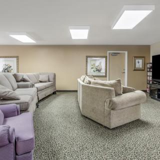 A spacious living room with multiple sofas and a large television.