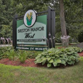 A sign for Briarcliff Manor West surrounded by lush foliage and landscaping.