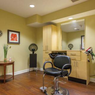 A modern hair salon setup featuring a styling chair and mirror, complemented by sleek cabinetry and warm decor.