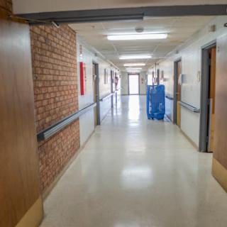 A well-lit hospital corridor featuring smooth walls and doors, creating a clean and organized environment.
