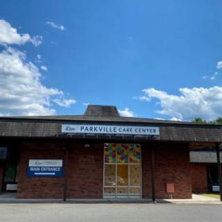 A brick building under a blue sky with scattered clouds, featuring a prominent entrance and signage.