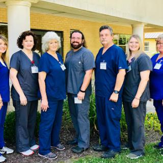 A dedicated healthcare team posing together in front of their facility.