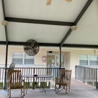 A covered outdoor patio with rocking chairs and a ceiling fan.