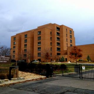 A view of a multi-story brick residential building surrounded by a gated perimeter.
