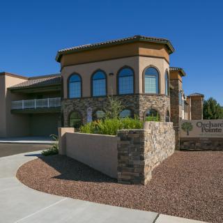 A modern office building with stone accents and neatly landscaped surroundings under a clear blue sky.