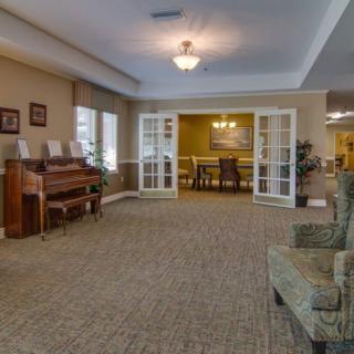 Spacious living room with a piano and an adjoining dining area.