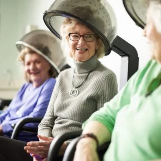 Elderly women enjoying a relaxing conversation under hair dryers at a salon.