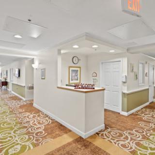 A well-lit hallway with patterned carpeting and framed artwork on the walls.