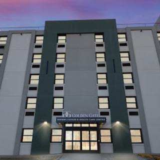 A modern building facade showcasing a well-lit entrance and multiple windows, set against a twilight sky.