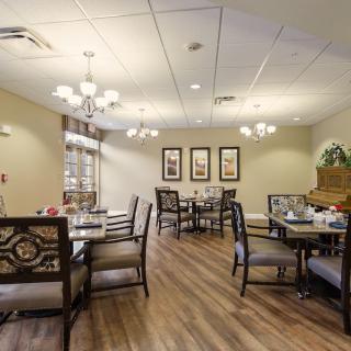 A well-lit dining room with elegant furniture and chandeliers.
