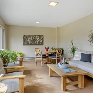 A cozy living room with natural lighting, featuring wooden furniture and indoor plants.
