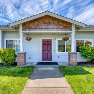 A charming residential house with a red front door, surrounded by greenery and a clear blue sky backdrop.