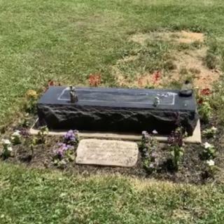 A gravestone surrounded by flowers in a cemetery garden.