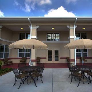 An outdoor patio area with tables and chairs under large umbrellas in front of a building.
