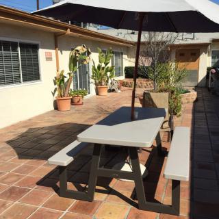 A sunny patio with a picnic table and umbrella surrounded by potted plants.