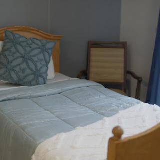A cozy bedroom featuring a neatly made bed with a decorative pillow and a simple chair in the corner.