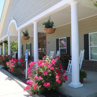 A charming porch with white columns and rocking chairs, adorned with vibrant flowers and hanging baskets.