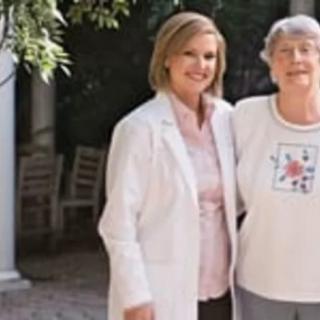 A doctor stands outside with an elderly woman.