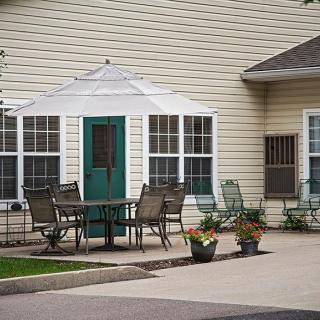 A cozy outdoor patio area with chairs and a table near a house.