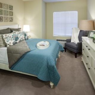 A modern bedroom with a neatly made bed, featuring blue accents and stylish decor.
